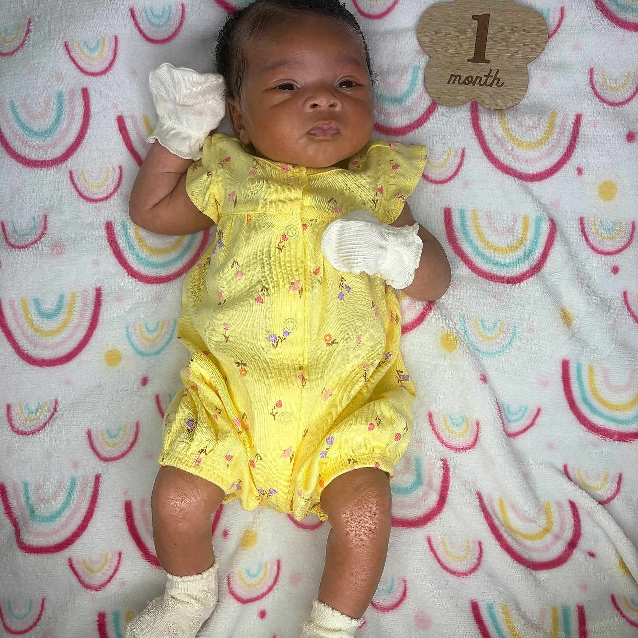 Sunjai joined the competition — help win amazing prizes! adorable, baby, blanket, child, colorful, cute, indoors, infant, lying_down, mittens, newborn, one_month, patterned_blanket, portrait, rainbow_pattern, small, socks, soft_texture, wooden_plaque, yellow_clothing