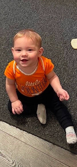 Kimber is registered to the contest to win money with this photo: baby, baby_toddler_clothing, cheek, child, face, finger, floor, flooring, fun, grass, happy, joy, leg, nose, person, sitting, skin, sleeve, smile, t_shirt