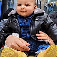 Adam a rejoint le concours — aidez-le/la à gagner de superbes lots ! baby, blue_shirt, casual_clothing, child, curtains, cute, face, hands, indoor, jeans, leather_jacket, person, portrait, reflection, smile, table, toddler, window, wood, yellow_boots