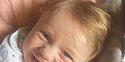 Romy a rejoint le concours — aidez-le/la à gagner de superbes lots ! baby, smile, bib, seat, cushion, child, infant, happy, face, clothing, pattern, indoor, cute, young, person, comfort, head, cheerful, closeup, portrait