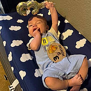 Maverick is registered to the contest to win money with this photo: baby, balloon, blanket, blue_clothing, child, cloud_pattern, cute, foot, furniture, hand, indoors, infant, lying_down, milestone, number_three, playful, portrait, smiling, wall, wooden_sign