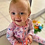 baby, child, playing, toy, onesie, pink_clothing, blue_eyes, smiling, indoor, floor, playmat, cute, happy, infant, person, portrait, sitting, hand, face, young