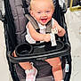 baby, stroller, pacifier, pink_bow, pink_sneakers, graco, happy, smiling, child, indoor, floor, toy, footwear, seatbelt, person, cute, infant, clothing, accessory, portrait