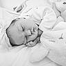 baby, sleeping, infant, bow, headband, blanket, plush_toy, soft, cozy, black_and_white, peaceful, cute, child, newborn, resting, portrait, indoors, closeup, toddler, sleep