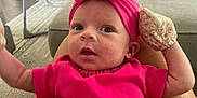 Irelynn joined the competition — help win amazing prizes! baby, baby_swing, carpet, couch, cozy, curious, fireplace, hand, headband, home, indoor, infant, legs, living_room, mittens, person, pink_clothing, seated, soft_lighting, wide_eyes
