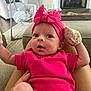 baby, infant, pink_clothing, headband, mittens, person, indoor, living_room, fireplace, baby_swing, carpet, couch, hand, legs, curious, wide_eyes, seated, cozy, home, soft_lighting