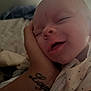 Irelynn is registered to the contest to win money with this photo: baby, sleeping, hand, tattoo, onesie, closeup, face, smile, infant, cozy, skin, person, resting, comfort, young, child, cute, portrait, indoor, soft