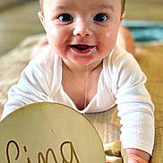 Malo participe au concours pour gagner de l'argent avec cette photo : baby, infant, child, drooling, smiling, face, portrait, white_clothing, blanket, wooden_sign, text, hand, lying_down, indoors, cute, young_child, soft_lighting, close_up, happy, cinq_mois