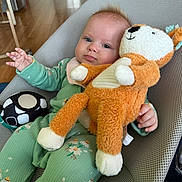 Mia is registered to the contest to win money with this photo: baby, infant, stuffed_animal, toy, green_onesie, baby_chair, mesh_chair, floor, wooden_floor, hand, face, expression, clothing, indoor, furniture, cushion, child, comfort, cute, plush_toy