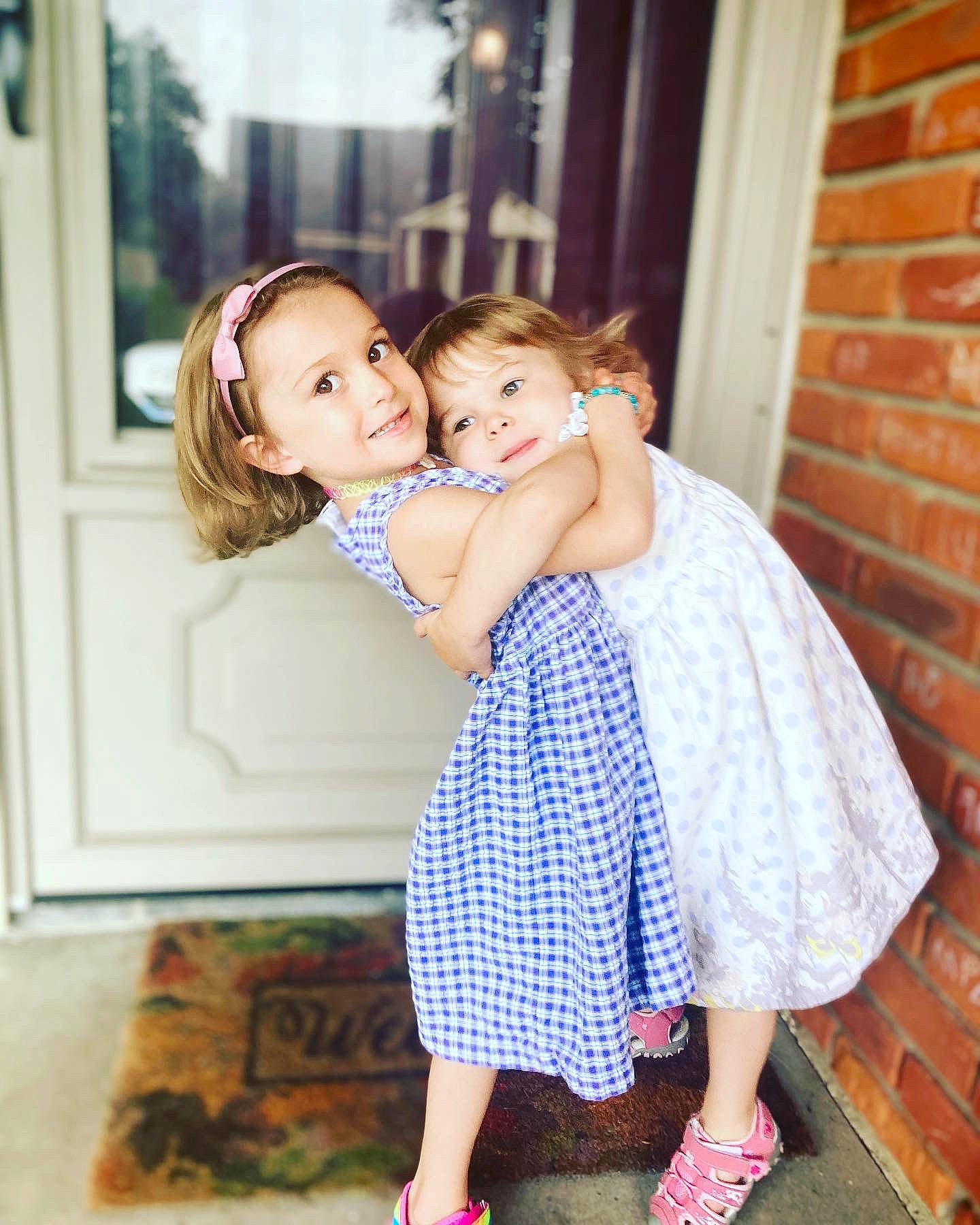 Amelia is registered to the contest to win money with this photo: baby_toddler_clothing, child, clothing, day_dress, dress, event, facial_expression, flash_photography, flooring, formal_wear, fun, gesture, happy, hug, joy, magenta, pattern, person, sandal, shoulder