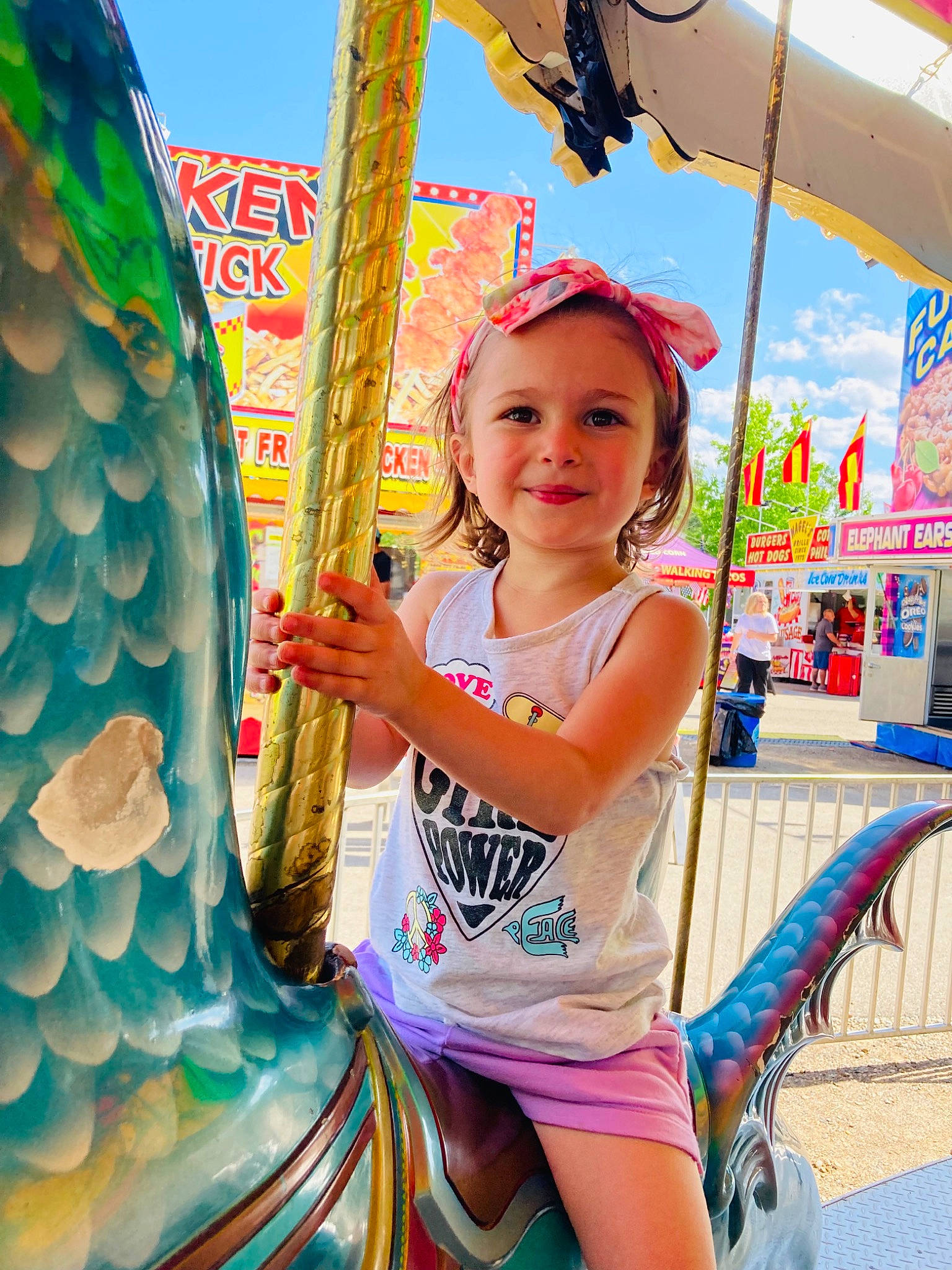 Amelia is registered to the contest to win money with this photo: amusement_park, amusement_ride, child, city, event, fun, happy, joy, leisure, magenta, nonbuilding_structure, person, playground, recreation, shorts, sky, smile, snapshot, summer, toddler