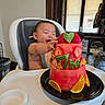 baby, blinds, celebration, child, clothing, food, fruit_cake, happy, high_chair, home, indoor, orange_slices, person, plate, smiling, strawberries, table, watermelon, window, wood_floor