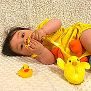 Akira a rejoint le concours — aidez-le/la à gagner de superbes lots ! baby, child, yellow_clothing, toy, rubber_duck, plush_toy, blanket, cute, infant, lying_down, soft_texture, indoors, playtime, smiling, face, hand, bright_color, childhood, adorable, young