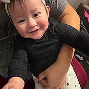 Kamila joined the competition — help win amazing prizes! adult_hand, arm, baby, black_shirt, child, closeup, clothing, cute, face, happy, headband, holding, human, indoor, person, portrait, reaching_hand, sitting, smile, white_pants