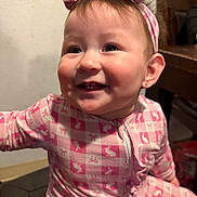 Kamila is registered to the contest to win money with this photo: baby, child, smiling, pink, headband, indoors, clothing, face, person, happy, cute, cheeks, teeth, portrait, hand, furniture, home, girl, pattern, headwear