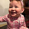 baby, child, smiling, pink, headband, indoors, clothing, face, person, happy, cute, cheeks, teeth, portrait, hand, furniture, home, girl, pattern, headwear