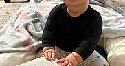 Kamila is registered to the contest to win money with this photo: baby, black_shirt, blanket, book, carpet, child, cozy, cute, floor, happy, headband, home, indoor, person, reading, sitting, smiling, stuffed_animal, toy, young