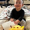 baby, black_shirt, blanket, book, carpet, child, cozy, cute, floor, happy, headband, home, indoor, person, reading, sitting, smiling, stuffed_animal, toy, young