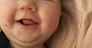 Nova is registered to the contest to win money with this photo: baby, blanket, cheeks, child, close_up, clothing, cute, dinosaur_print, face, happy, head, indoors, infant, person, portrait, skin, smiling, soft, tongue_out, young