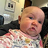 baby, child, face, expression, indoor, clothing, floral_pattern, person, portrait, head, skin, eyes, mouth, cheeks, doctor_office, signage, jacket, door, light, wall