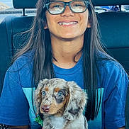 Piper Morones joined the competition — help win amazing prizes! person, child, glasses, braces, puppy, dog, car_interior, seat, blue_shirt, long_hair, smile, young, pet, holding, cute, sitting, window, daylight, happy, animal