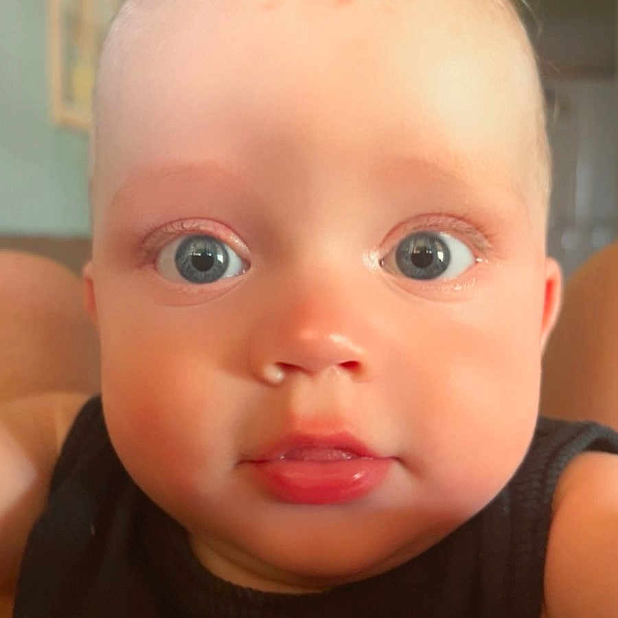 Marli Lima Tedesco a rejoint le concours — aidez-le/la à gagner de superbes lots ! baby, black_shirt, blue_eyes, cheeks, child, close_up, curly_hair, cute, expression, eyelashes, face, indoor, infant, looking, mouth, nose, person, portrait, skin, young