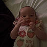 baby, infant, onesie, bed, blanket, clothing, person, child, cute, fruit, flower, text, sleepwear, hand, face, lying_down, indoors, soft_light, sweet, young