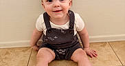 Lucas is registered to the contest to win money with this photo: baby, child, smiling, sitting, floor, tile, socks, romper, clothing, indoor, person, head, face, happy, skin, young, cute, babywear, wall, texture