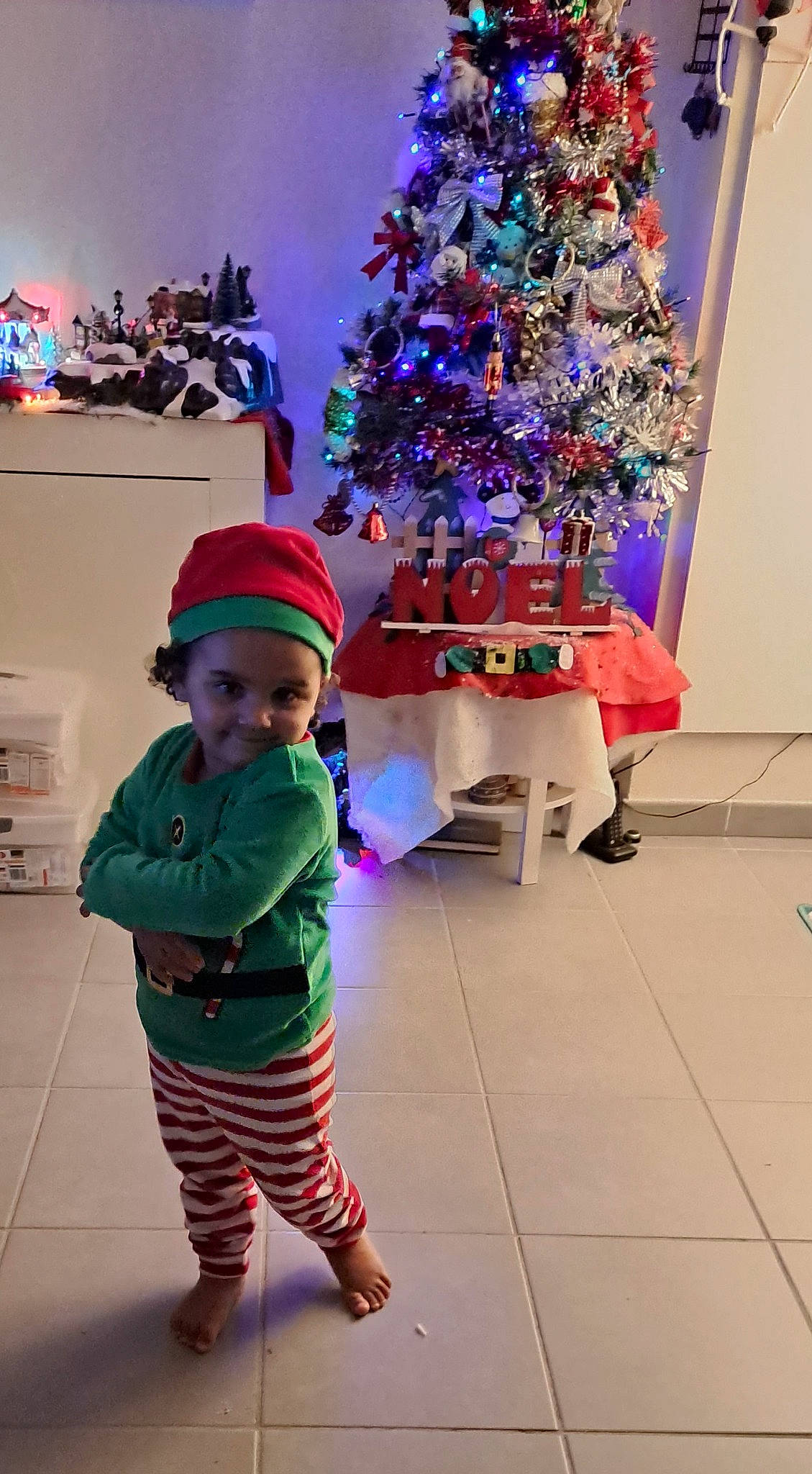 Linayah participe au concours pour gagner de l'argent avec cette photo : baby_toddler_clothing, christmas, christmas_decoration, christmas_ornament, christmas_tree, event, fun, headwear, holiday, holiday_ornament, joy, lighting, magenta, ornament, person, pink, plant, purple, sleeve, standing