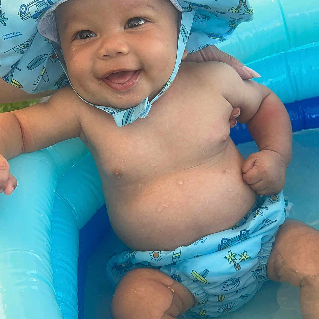 Armani is registered to the contest to win money with this photo: baby, cap, clothing, diaper, face, happy, hat, head, outdoors, person, photography, pool, portrait, shorts, sitting, smile, summer, swimmingpool, swimwear, water