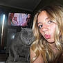 blonde_hair, cabinet, casual, cat, chair, curtains, expression, floor, furniture, gray_cat, home, indoor, living_room, long_hair, pet, portrait, puckered_lips, selfie, television, woman