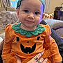 Leia is registered to the contest to win money with this photo: baby, child, smiling, pumpkin_outfit, orange_clothing, headband, tattooed_hand, indoor, couch, cozy, cute, portrait, person, infant, happy, tulle_skirt, long_sleeve, home, seated, face