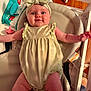 baby, infant, headband, bow, smile, arms, clothing, seat, cushion, pacifier, baby_wipes, wood_floor, indoor, person, cute, happy, child, closeup, plush, relaxed