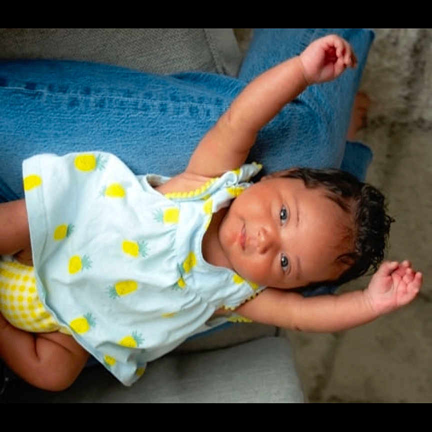 Amina is registered to the contest to win money with this photo: baby, bodypart, clothing, dress, face, finger, hand, happy, head, jeans, mouth, newborn, pants, person, photography, portrait, sitting, smile, t_shirt, teeth