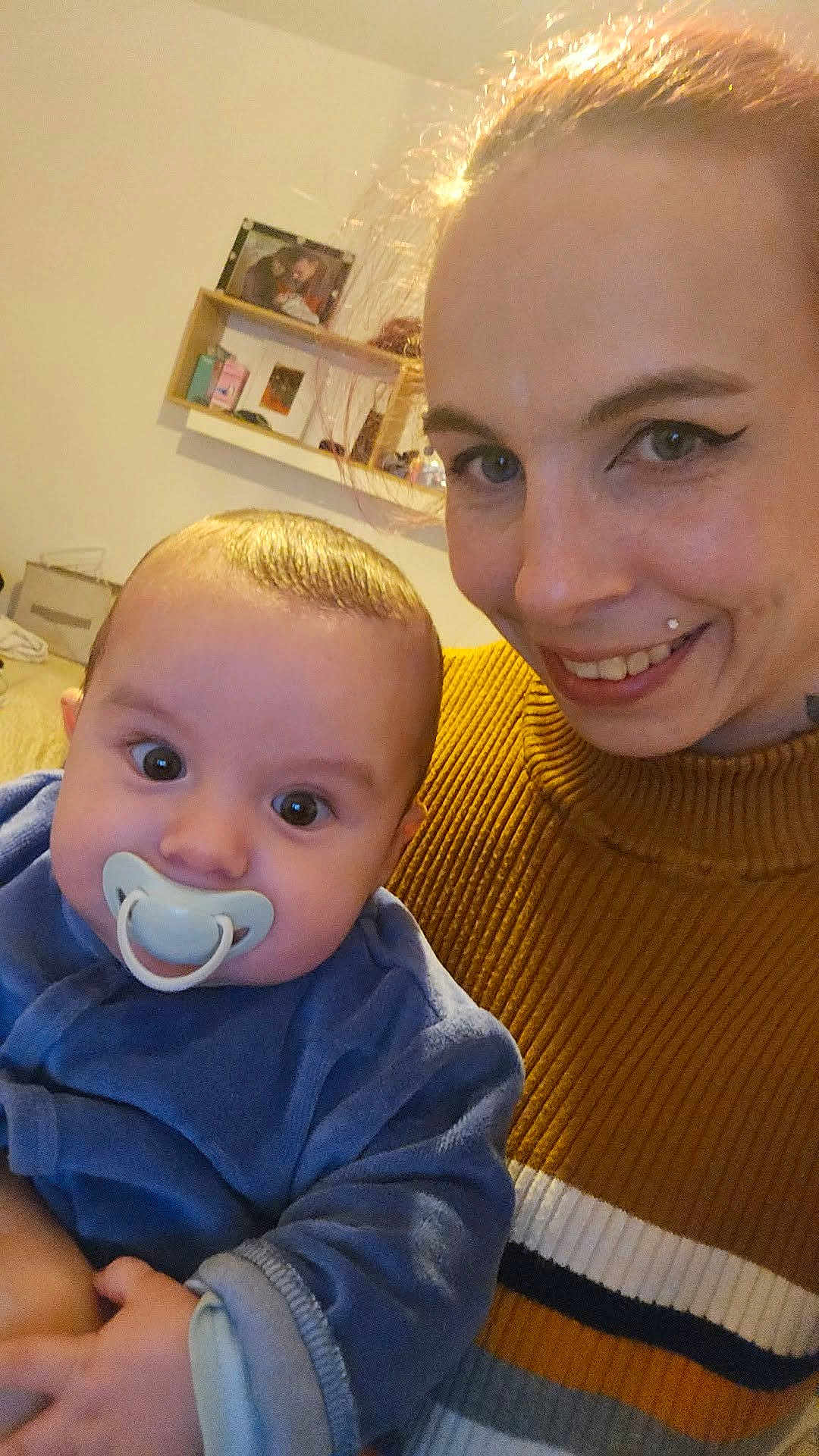 Thyago Rambert a rejoint le concours — aidez-le/la à gagner de superbes lots ! baby, infant, pacifier, adult, woman, smile, close_up, portrait, indoor, sweater, striped_sweater, holding, eyes, face, hair, skin, shelf, picture_frame, living_room, cozy