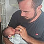 affection, baby, beard, black_shirt, care, closeup, clothing, family, gentle, holding, human, indoor, love, man, newborn, parent, portrait, ring, sleeping, tender