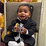 baby, child, tuxedo, suit, bow_tie, chair, balloons, leopard_print, pink_balloon, smiling, happy, socks, indoor, celebration, party, cute, portrait, person, holding_object, festive
