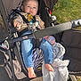 Rivver is registered to the contest to win money with this photo: baby, stroller, child, jeans, sweater, bottle, blanket, outdoor, grass, sunlight, foot, face, seatbelt, person, toy, wheel, path, comfort, expression, casual