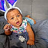 baby, bunny_ears, pacifier, bed, blanket, child, curious, expression, face, headwear, indoor, infant, laying_down, person, plush, purple, shirt, shorts, toy, young_child