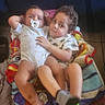 Sa'Riah is registered to the contest to win money with this photo: child, baby, infant, pacifier, blanket, curly_hair, toddler, clothing, sibling, indoor, floor, tile_floor, cute, legs, barefoot, sitting, holding, expression, person, young