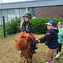 Ambre a rejoint le concours — aidez-le/la à gagner de superbes lots ! boots, building, cap, child, children, fence, friendship, fun, gloves, grass, happy, helmet, horse, jacket, nature, outdoor, play, pony, riding, smile