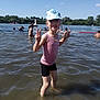 child, girl, water, lake, summer, cap, tank_top, shorts, peace_sign, people, outdoor, sunny, nature, trees, inflatable, float, recreation, swimming, happy, fun