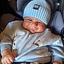 baby, child, smile, hat, knit_hat, blue_clothing, sweater, animal_print, car_seat, infant, cute, chubby_cheeks, hand_made_label, clothing, person, portrait, indoors, happy, young_child, casual