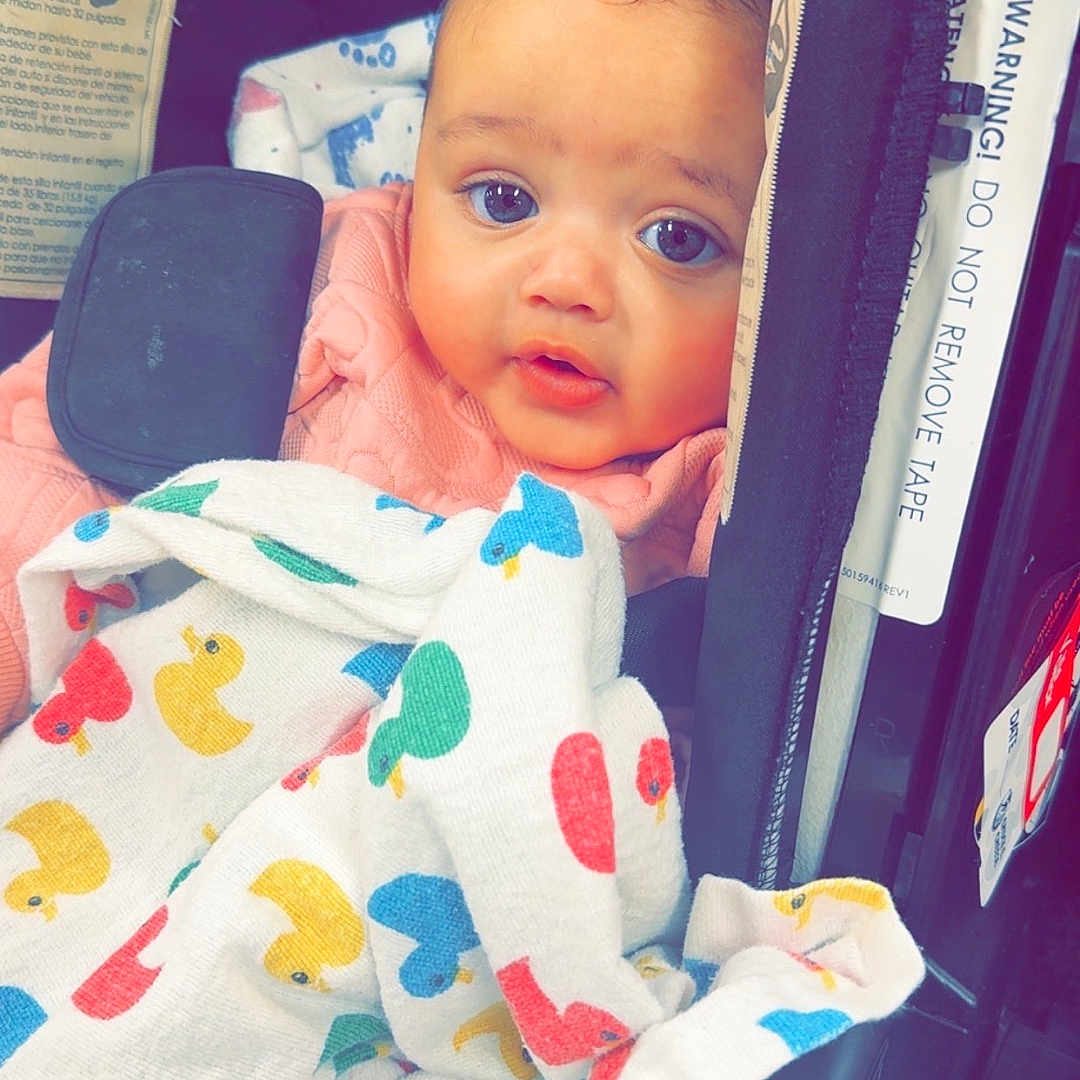 Saroya joined the competition — help win amazing prizes! baby, baby_blanket, blanket, blue_eyes, car_seat, child, child_seat, closeup, comfort, cute, duck_pattern, expression, face, indoor, infant, pink_clothing, portrait, safety_warning, seatbelt, young_child