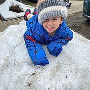 Jayden joined the competition — help win amazing prizes! child, toddler, smiling_child, knit_hat, beanie, blue_jacket, snow, snow_pile, outdoor, sidewalk, driveway, parked_car, boots, playful, teeth, happy, portrait, winter, hat, cute