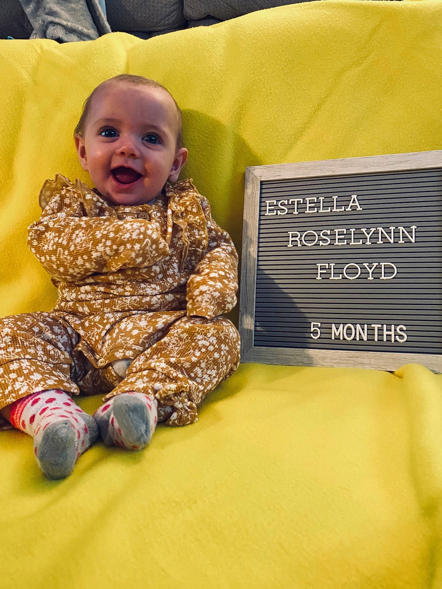 Estella joined the competition — help win amazing prizes! baby, baby_laughing, baby_toddler_clothing, child, comfort, couch, flooring, fun, happy, human_leg, knee, person, product, room, sitting, sleeve, smile, textile, toddler, wood