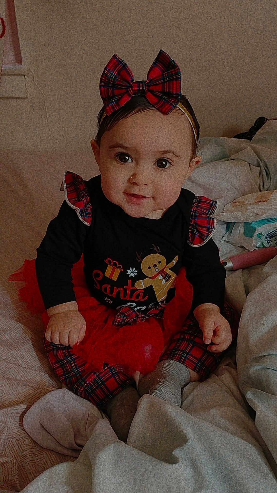 Naylani joined the competition — help win amazing prizes! baby, child, girl, plaid, bow, holiday, christmas, bed, blanket, clothing, cute, sitting, portrait, indoors, smile, festive, toddler, red, black, warm