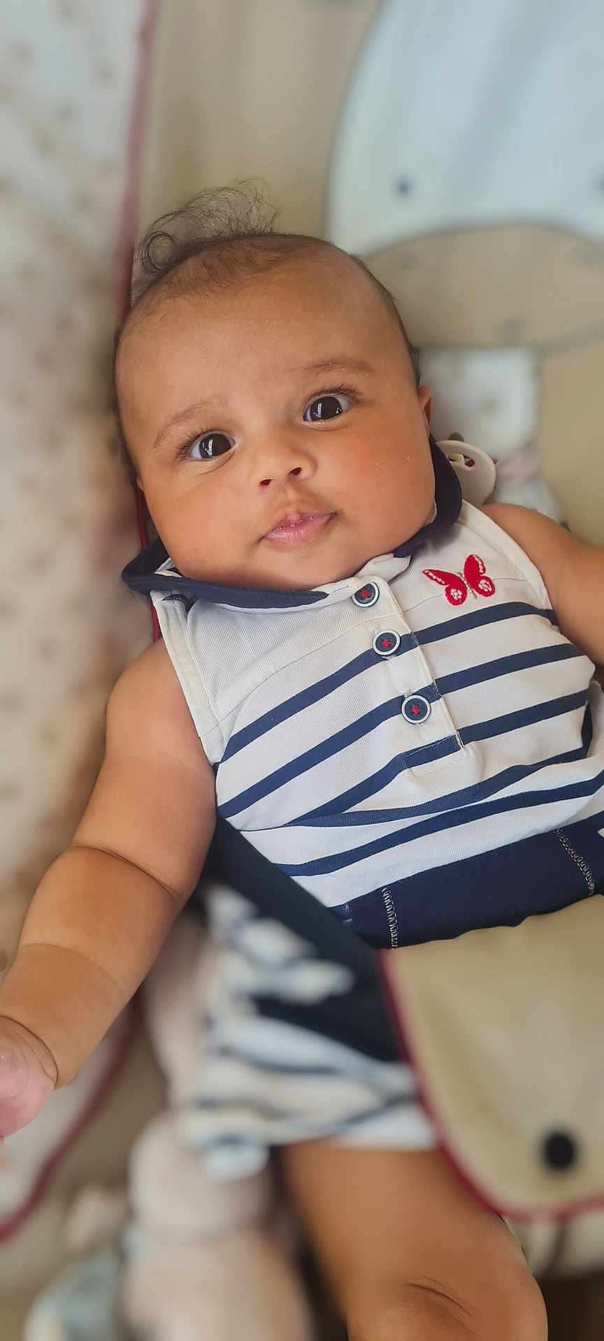Cassy participe au concours pour gagner de l'argent avec cette photo : baby, infant, child, face, eyes, clothing, striped_outfit, butterfly_patch, soft_background, cushion, cute, portrait, skin, arm, hand, lying_down, indoors, closeup, person, smiling