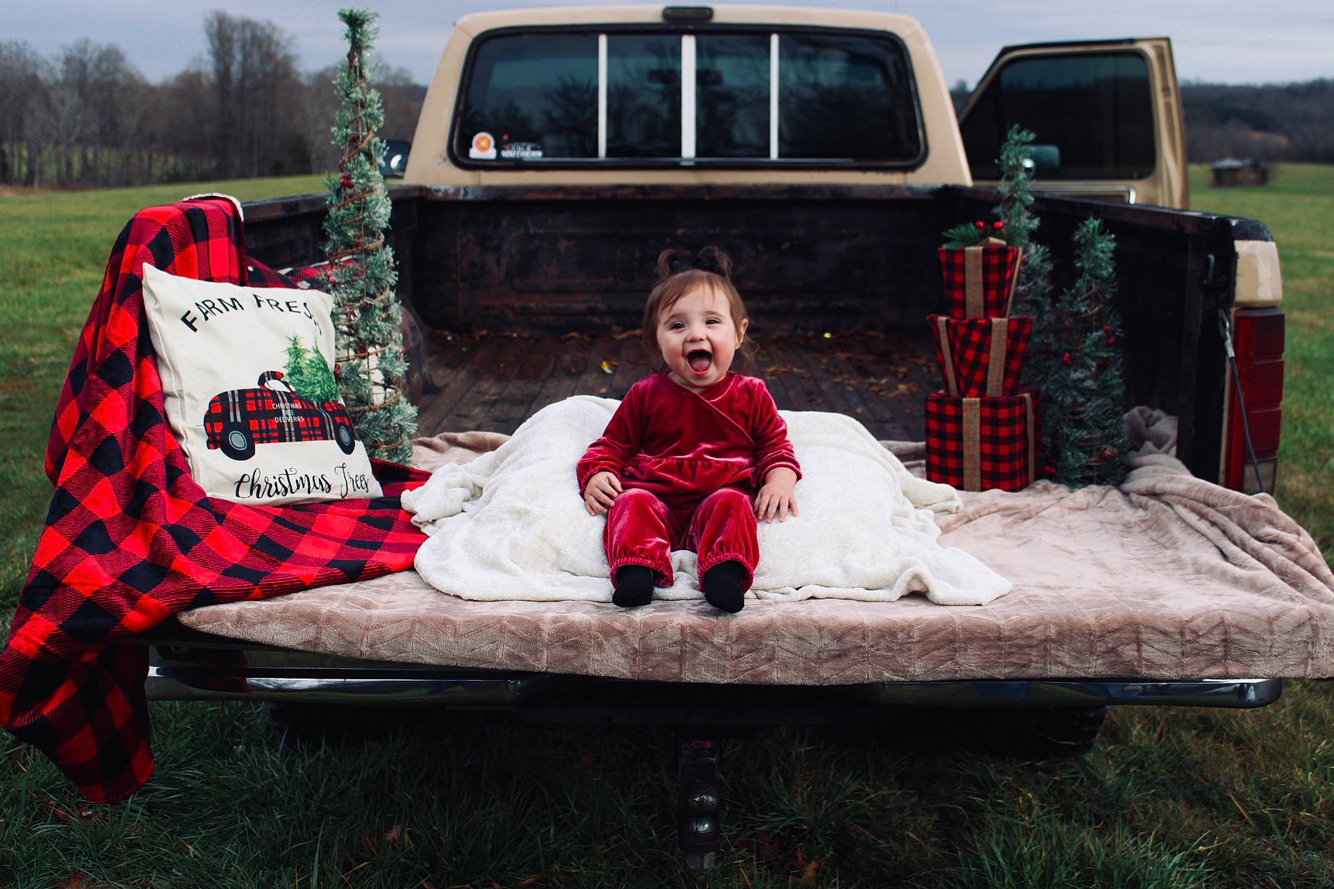 Brinley is registered to the contest to win money with this photo: automotive_exterior, automotive_tire, bumper, car, child, family_car, fun, grass, jacket, leisure, motor_vehicle, person, plant, recreation, sitting, sky, tire, toddler, tree, vehicle