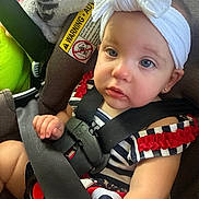 Bellamy is registered to the contest to win money with this photo: baby, blanket, blue_eyes, car_seat, child, cute, earrings, face, headband, indoor, infant, person, portrait, red_ruffles, safety_harness, seatbelt, skin, small_hand, striped_dress, warning_label